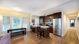 an open kitchen with a table and a refrigerator at Harrison Lake View Suites in Harrison Hot Springs