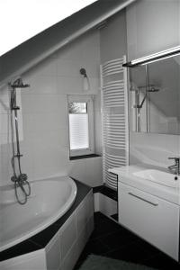 ein weißes Badezimmer mit einer Badewanne und einem Waschbecken in der Unterkunft Ferienwohnung am Kurpark in Bad Nenndorf