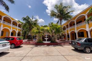 ein Parkplatz vor einem Gebäude mit Palmen in der Unterkunft Hotel los Arcos in Izamal