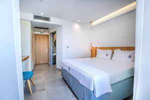 a bedroom with a white bed and a blue chair at Senso Suites in Nea Peramos