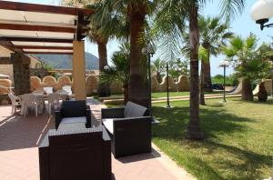 d'une terrasse avec des chaises, des tables et des palmiers. dans l'établissement Villa lipari, à Cefalù