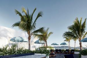 a patio with palm trees and chairs and umbrellas at The Ville Resort - Casino in Townsville