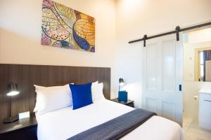 a hotel room with a large bed and a painting on the wall at The Mile End Hotel in Adelaide