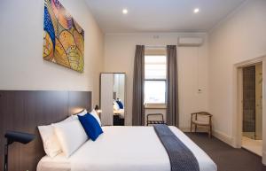 a bedroom with a large bed with blue pillows at The Mile End Hotel in Adelaide