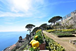 un jardín con flores amarillas en una colina junto al océano en Il Centro Storico Ravello, en Ravello