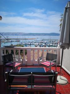 a table and chairs on a balcony with a view of a harbor at MIRAMAR Apartman in Novi Vinodolski