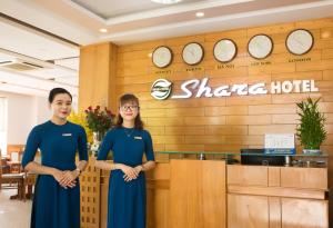 dos mujeres de pie en frente de un hotel shaza en Shara Hotel Da Nang, en Da Nang