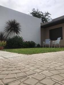 查斯科穆斯Departamento en Chascomús a dos cuadras de laguna的两把椅子坐在建筑物旁边的草上 更多6张照片