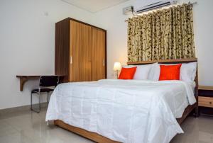 Cloud9Homes Serviced Apartments في حيدر أباد: غرفة نوم مع سرير أبيض كبير مع وسائد حمراء