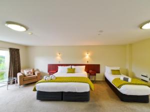 1 dormitorio con 2 camas y 1 silla en ASURE Avenue Motor Lodge, en Timaru
