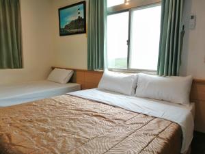 una camera d'albergo con due letti e una finestra di Love With Dolphin B&B a Magong