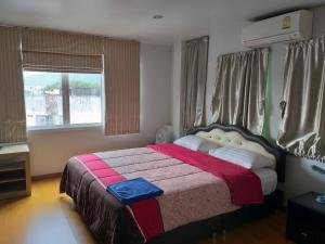 a bedroom with a bed with a red blanket and a window at Baan Malee in Phuket Town