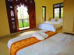 a bedroom with two beds and two windows at Mountain View House in Kintamani