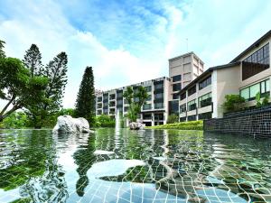 una piscina de agua con una fuente frente a un edificio en Spring Hill Resort, en Tianliao