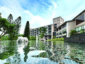 a pool of water with a fountain in front of a building at Spring Hill Resort in Tianliao