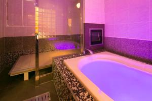 uma casa de banho com uma grande banheira com iluminação roxa em Hotel Bypass (Adult Only) em Koriyama