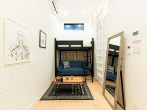 Habitación con cama elevada y sofá azul en TRIP POD TAKASAGO B, en Fukuoka