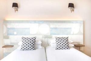 two beds in a bedroom with two pillows at Best Western Plus Antibes Riviera in Antibes