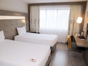 a hotel room with two beds and a desk at Novotel RJ Porto Atlantico in Rio de Janeiro