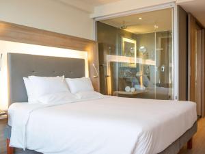 a bedroom with a large white bed with a glass wall at Novotel RJ Porto Atlantico in Rio de Janeiro