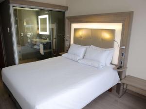 a bedroom with a large white bed and a bathroom at Novotel RJ Porto Atlantico in Rio de Janeiro