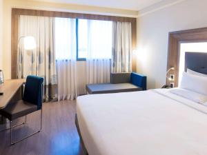 a hotel room with a large white bed and a desk at Novotel RJ Porto Atlantico in Rio de Janeiro