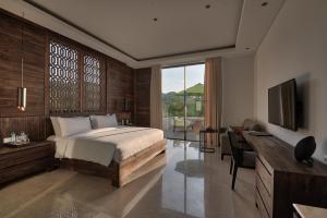 Dormitorio con cama, escritorio y TV en Kemangi Bed and Breakfast, en Kuta Lombok