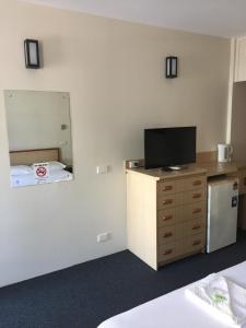 um quarto com televisão numa cómoda com espelho em Darwin Poinciana Inn em Darwin