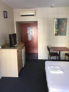 ein Hotelzimmer mit einem Bett, einem Schreibtisch und einem Tisch in der Unterkunft Darwin Poinciana Inn in Darwin