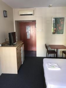 a hotel room with a bed and a desk and a table at Darwin Poinciana Inn in Darwin