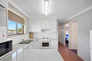 a white kitchen with a sink and a stove at Clifford Gardens Motor Inn in Toowoomba