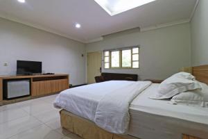 a bedroom with a large bed and a television at Hotel Sampaga in Banjarmasin