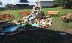 a small waterfall in a park with benches and a fountain at Camere de închiriat AnneMaryy in Arbore
