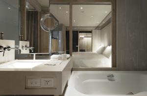 a bathroom with a tub, sink, and mirror at Gloria Residence in Taipei