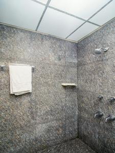 a bathroom with a shower with a towel on the wall at HOTEL BOOPATHI Madurai in Madurai
