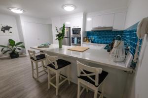 a kitchen with a white counter and some chairs at Sanctuary Beach Retreat in Gold Coast