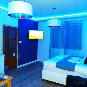 a blue bedroom with a bed and two lights at Pál Villa - Premium Apartments - Kecskemét in Kecskemét