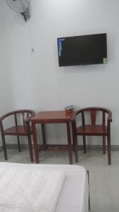 Cette chambre dispose de 2 chaises, d'une table et d'une télévision. dans l'établissement Khách Sạn Bảy Tâm Khách Sạn Gần Dinh Thầy Thím Biển LaGi, à La Gi