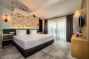 a bedroom with a large white bed and a stone wall at Isola 12 Hotel in Kas