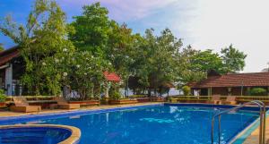 a large blue swimming pool with chairs and trees at Punnamada Resort in Alleppey