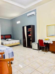 1 Schlafzimmer mit 2 Betten, einem Tisch und einem Stuhl in der Unterkunft Sola Gracia Guest House & Kost in Palangkaraya