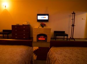 a bedroom with a fireplace and a tv on the wall at The Firs in Nuwara Eliya