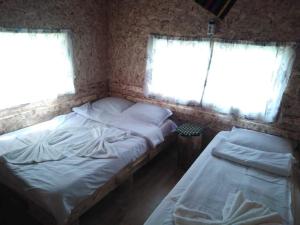 two twin beds in a room with two windows at Teo's Guest House in Dospat