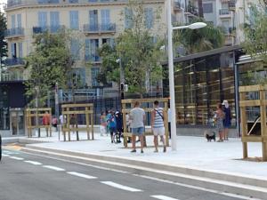 un grupo de personas de pie en una acera al lado de una calle en Hotel Victor Hugo Nice, en Niza