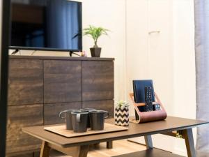 a coffee table with three mugs on it next to a tv at TRIP POD MINOSHIMA A in Fukuoka