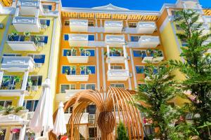 an apartment building with an arch and an umbrella at Sweet Homes Apartments in Sunny Beach