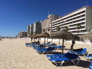 Luxury Oceanfront triplex in Cadiz في كاديز: مجموعة من الكراسي والمظلات على الشاطئ