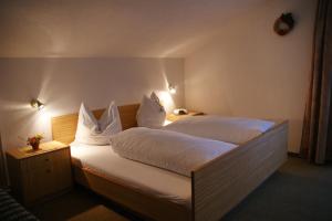 Schlafzimmer mit einem Bett mit weißer Bettwäsche und Kissen in der Unterkunft Haus Venetblick in Wenns