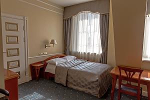 a bedroom with a bed and a desk and a window at Europe Hotel in Minsk