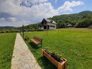 a park with a bench and flowers and a house at Holiday Home Drijenak in Kolašin